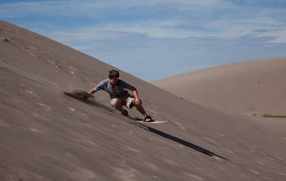 Ragazzo pratica sandboarding sulle dune del deserto
