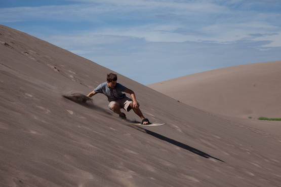 Ragazzo pratica sandboarding sulle dune del deserto