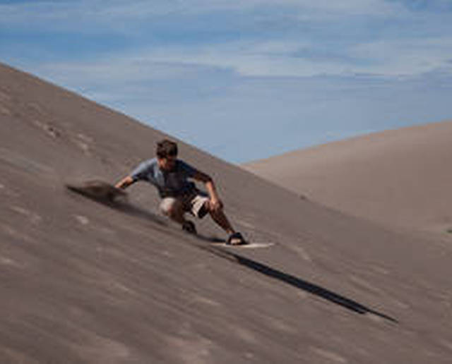 Ragazzo pratica sandboarding sulle dune del deserto